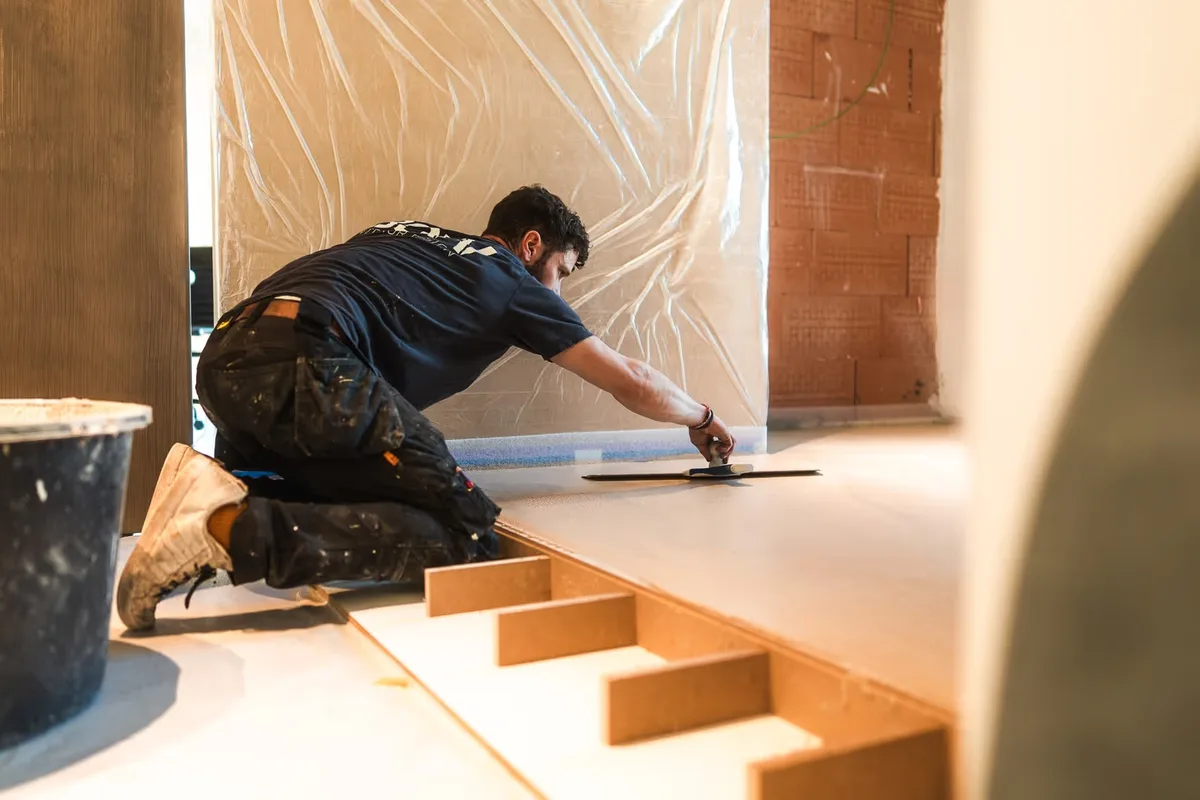 Un artisan BOW Design lisse une marche en béton ciré sur chantier